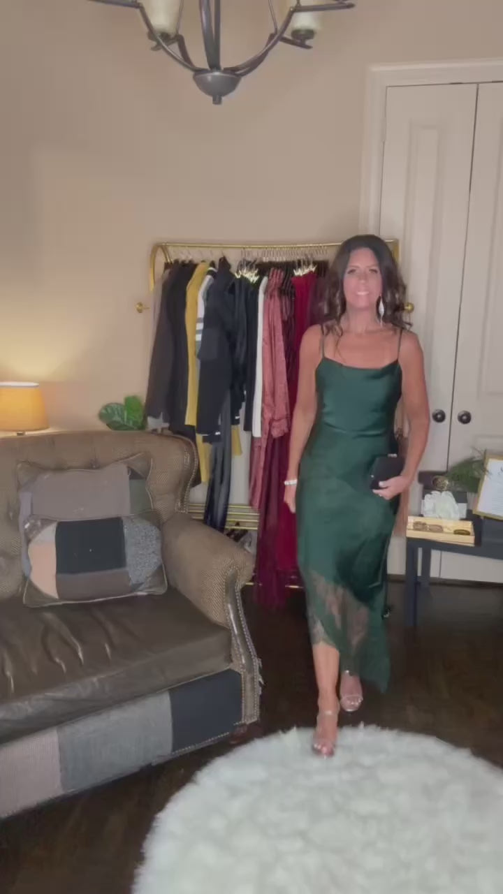Model is wearing an asymetrical satin dress with delicate lace trim in a rich hunter green color.