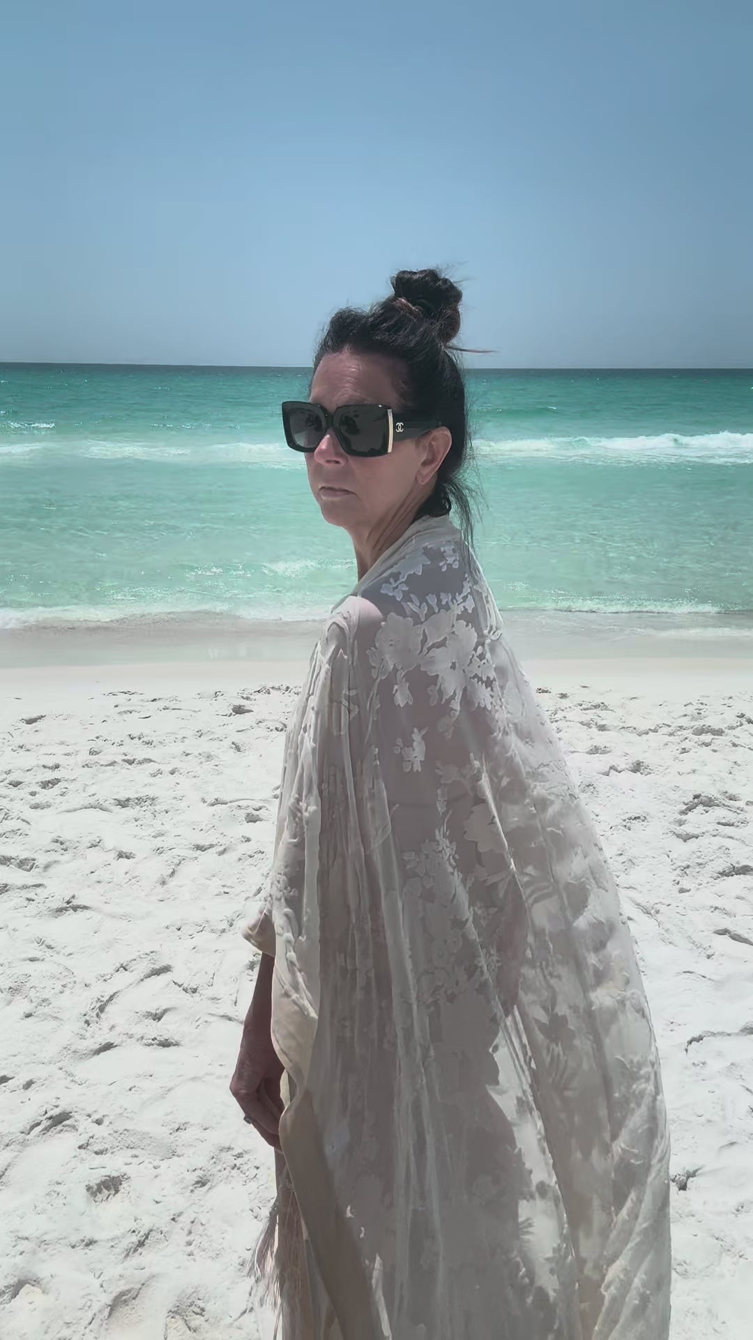 woman walking on beach with ocean background wearing ivory kimono