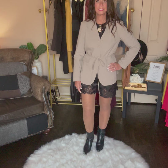Video of the taupe Perfect Layer Lightweight Tie Blazer with black lace-trim shorts, a necklace and black ankle boots.