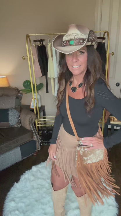 Woman modeling a tan fringe crossbody bag.