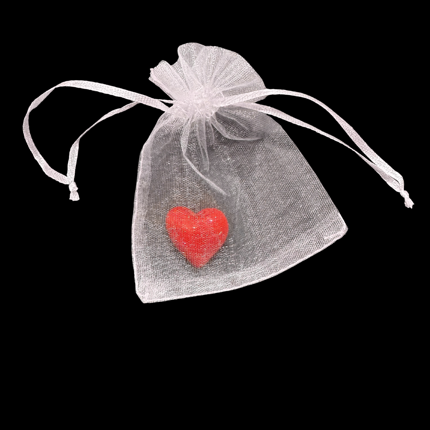 White organza bag with a red heart-shaped object on a black background